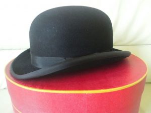Black bowler hat sitting upon a red cushion